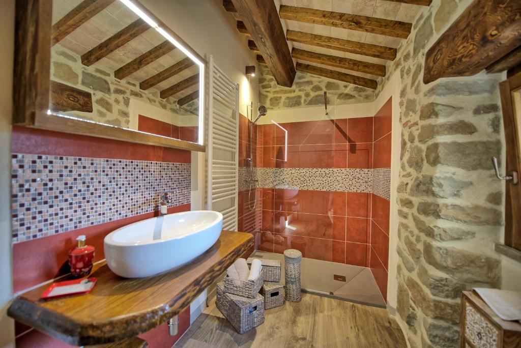 La salle de bains est pourvue d'un lavabo blanc et d'un mur en pierre. dans l'établissement Villa Mulino by PosarelliVillas, à Poggioni
