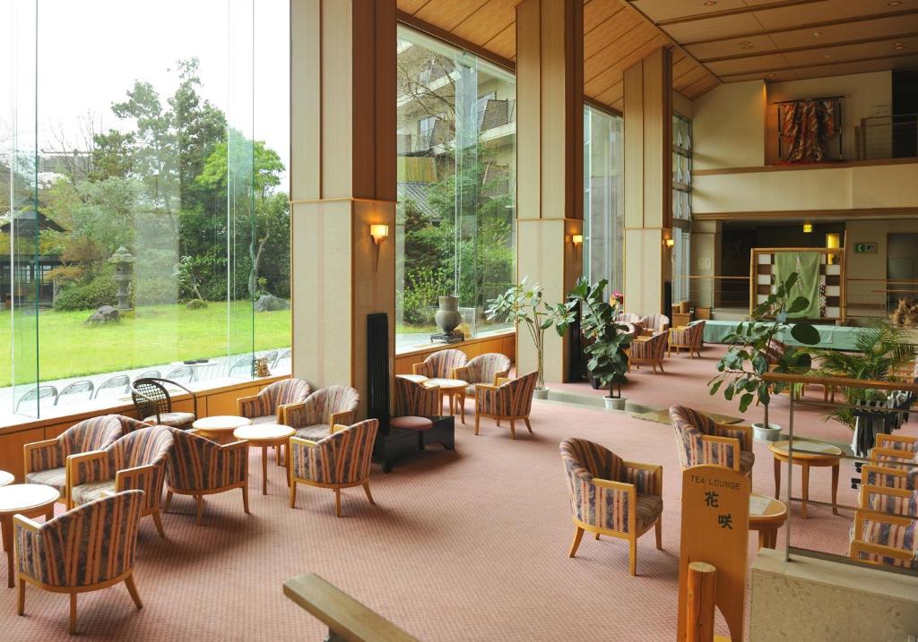- un hall avec des tables, des chaises et des fenêtres dans l'établissement Yufuin Kotobuki Hananosho, à Yufu