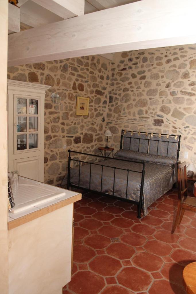 une chambre avec un lit dans un mur de pierre dans l'établissement Gîtes Mas de la Musardière, à Les Assions 37 autres photos