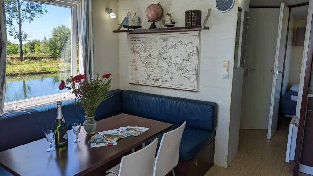 une salle à manger avec une table et un canapé bleu dans l'établissement Cottage flottant jacuzzi privé en option gamme supérieure, à Saint-Jean-de-Losne