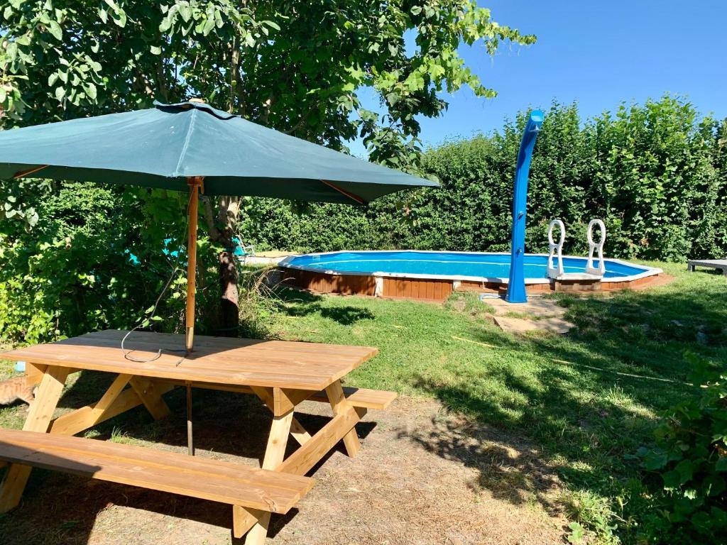 - une table de pique-nique avec un parasol à côté de la piscine dans l'établissement cabane bambou, à Huriel