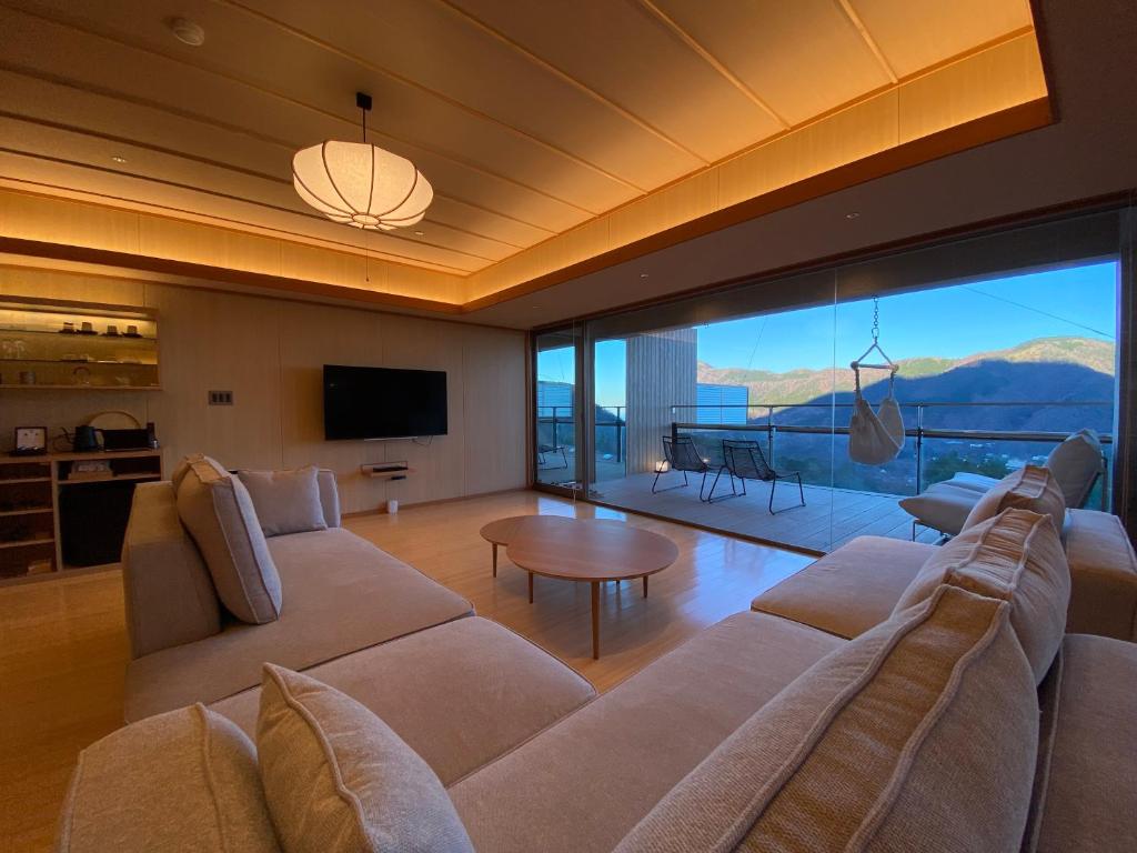 - un salon avec un grand canapé et une grande fenêtre dans l'établissement Gen Hakone Gora, à Hakone
