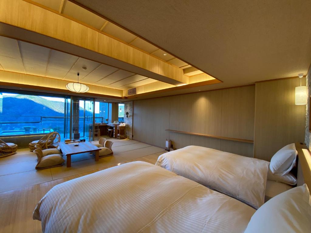 une chambre avec deux lits et une grande fenêtre dans l'établissement Gen Hakone Gora, à Hakone