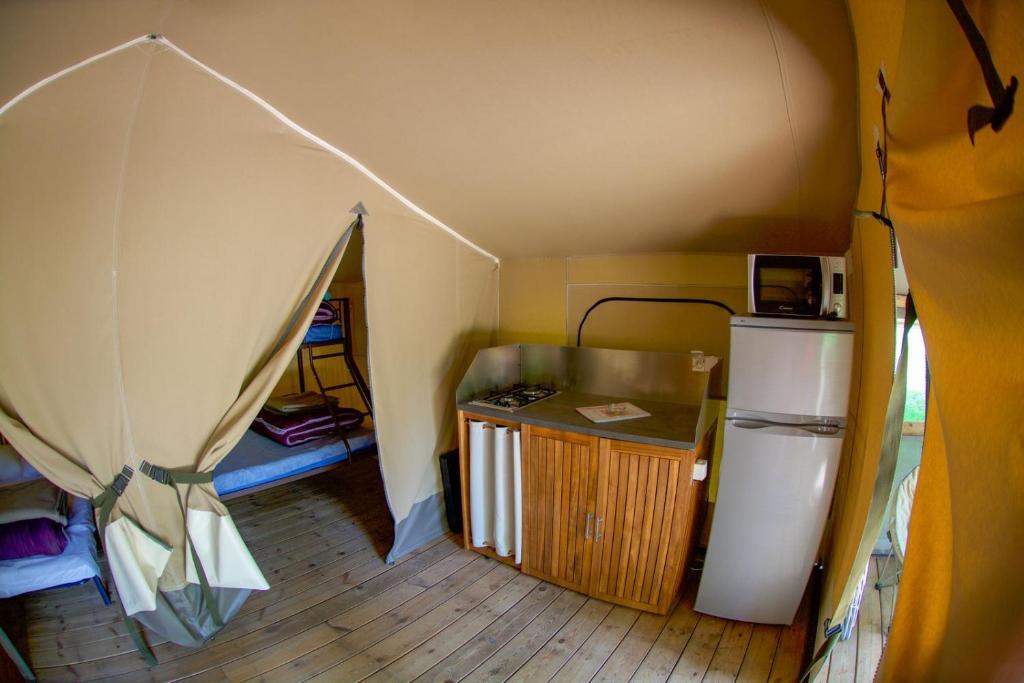 une petite chambre avec un réfrigérateur et une tente dans l'établissement Parc de vacances La Draille, à Souillac