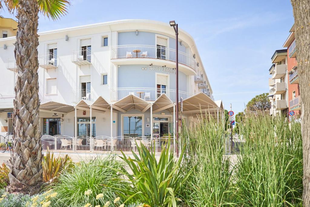 un bâtiment blanc avec des palmiers devant dans l'établissement Hotel Acquario, à Rimini