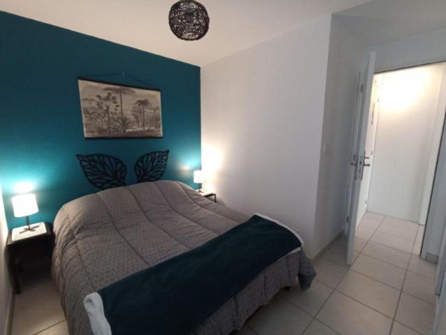 une chambre avec un lit et un mur bleu dans l'établissement Le Gîte de Marilou classé 3 étoiles Vallon Pont d'Arc, résidence privée piscine, à Vallon-Pont-dʼArc