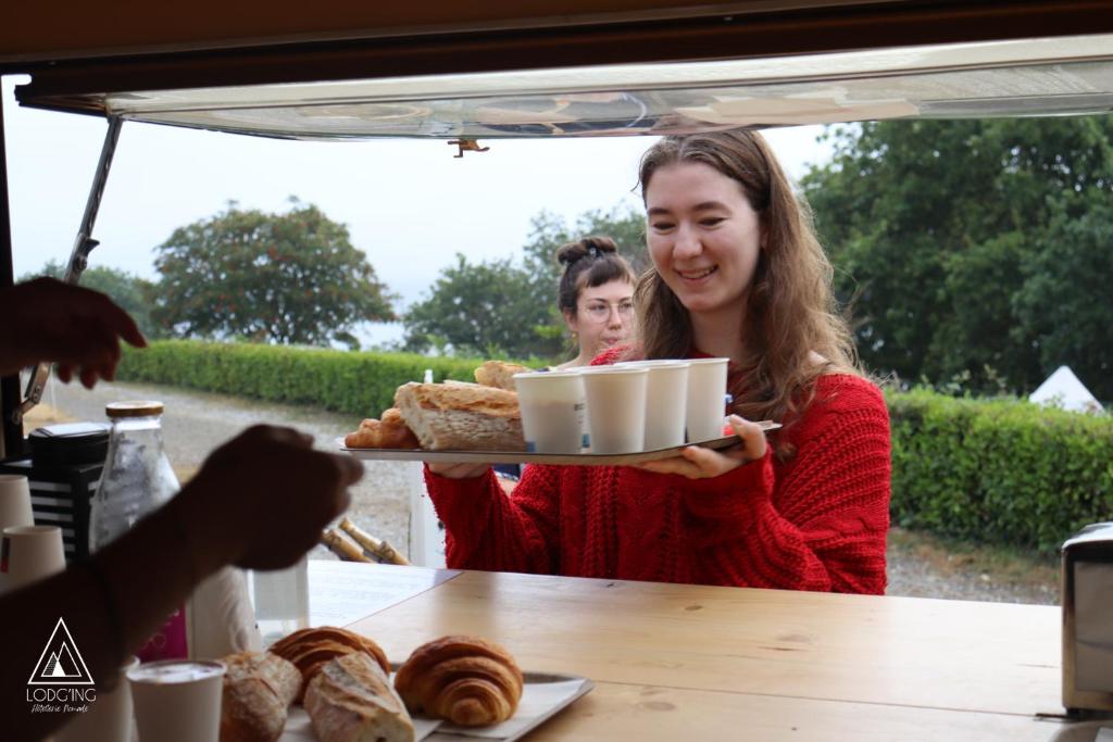 une femme tenant un plateau de pain et de viennoiseries dans l'établissement Lodg'ing Nature Camp Presqu'île Crozon, à Lanvéoc