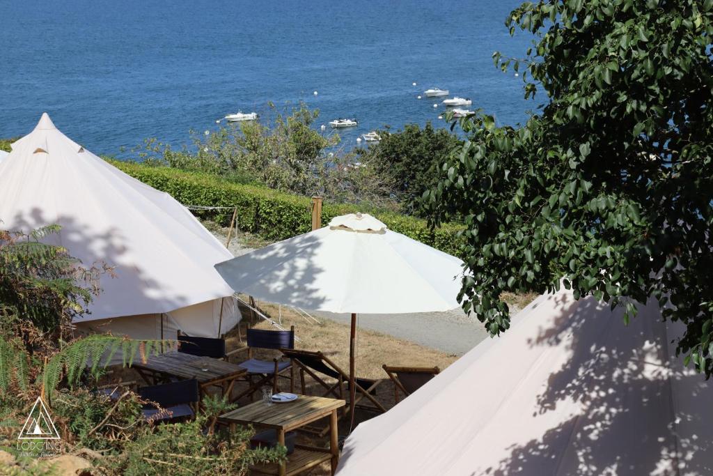 - deux parasols et des chaises blancs à côté de l'océan dans l'établissement Lodg'ing Nature Camp Presqu'île Crozon, à Lanvéoc