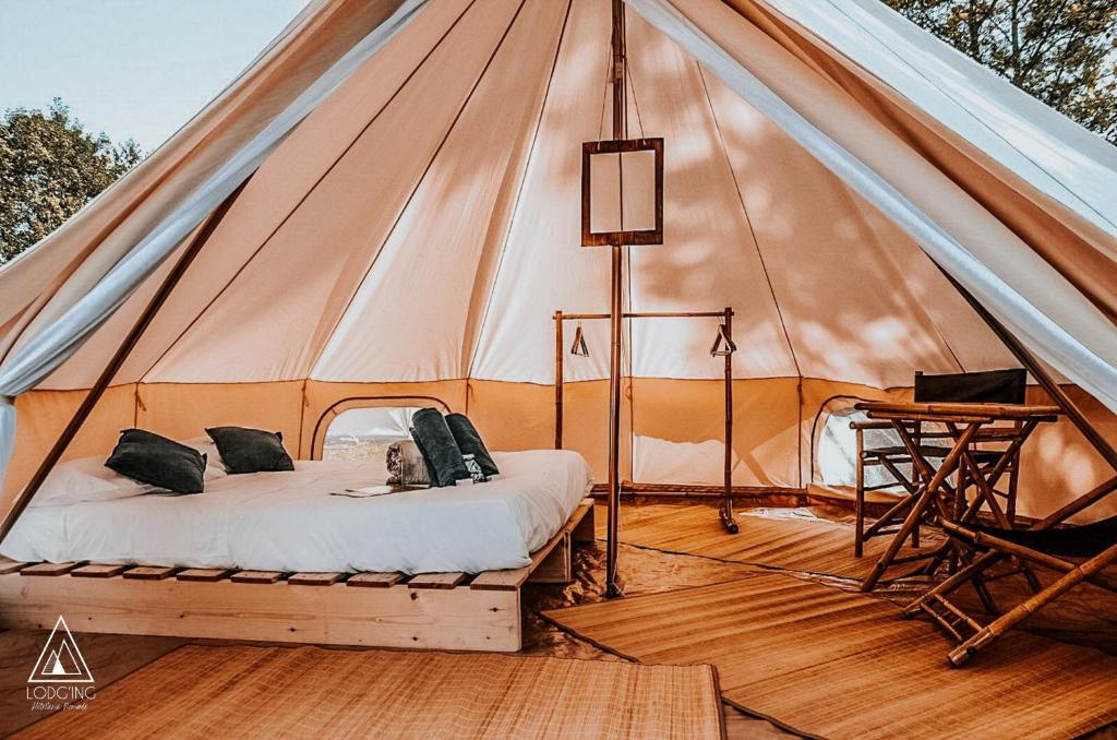 une tente avec un lit et un bureau à l'intérieur dans l'établissement Lodg'ing Nature Camp Châteaux de la Loire, à Cellettes
