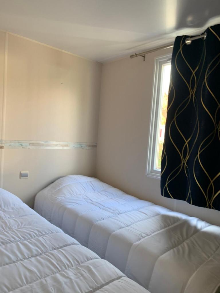 deux lits dans une petite pièce avec une fenêtre dans l'établissement Camping Le Montourey, à Fréjus 11 autres photos