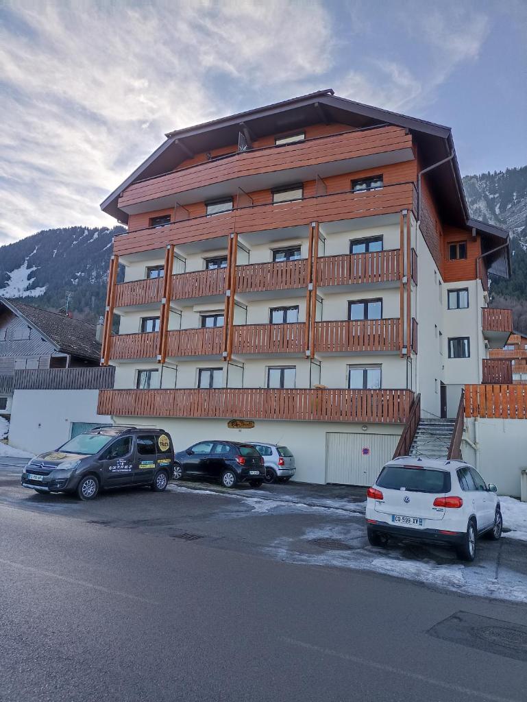 un grand bâtiment avec des voitures garées dans un parking dans l'établissement Appartement T2 idéal pour une famille, à Thollon-les-Mémises