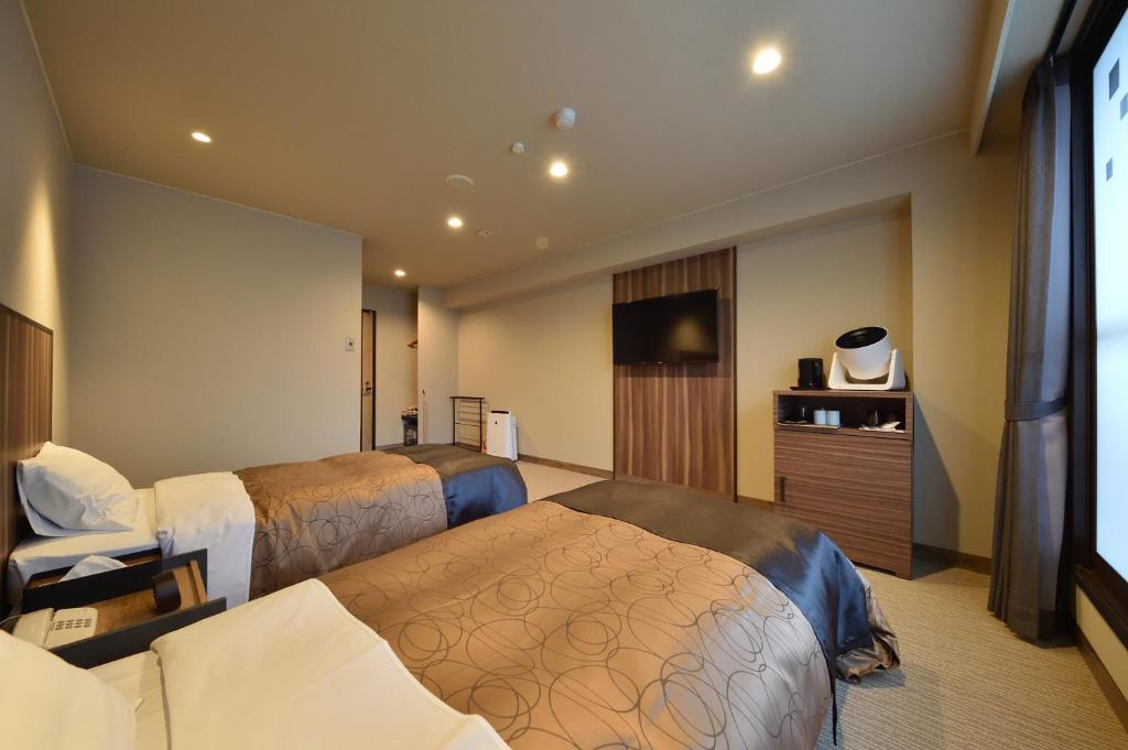 une chambre d'hôtel avec deux lits et une télévision à écran plat dans l'établissement 碧の美ゆゆaonobi yuyu旧湯元白金温泉ホテル, à Biei