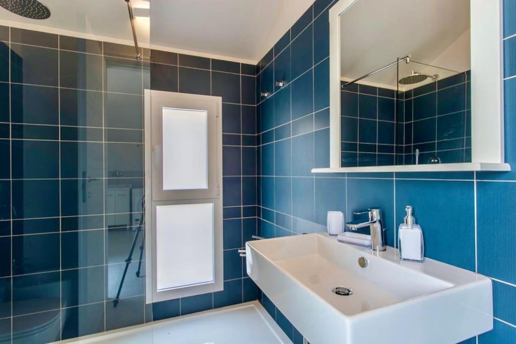 La salle de bains est pourvue de carrelage bleu, d'un lavabo et d'un miroir. dans l'établissement Domus Maulli - Villa sul mare, à Marina di Ragusa 13 autres photos