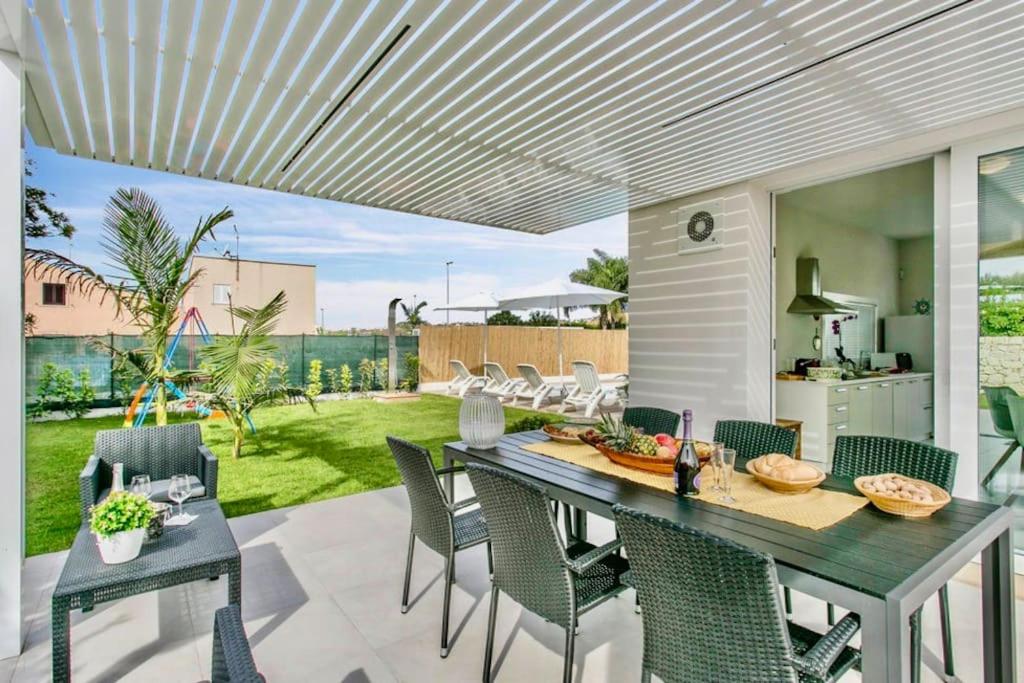 un patio avec une table et des chaises sur un patio dans l'établissement Domus Maulli - Villa sul mare, à Marina di Ragusa