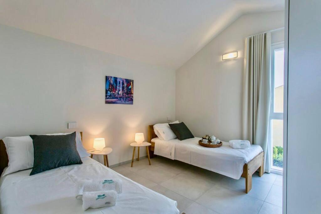 une chambre blanche avec deux lits et une fenêtre dans l'établissement Domus Maulli - Villa sul mare, à Marina di Ragusa