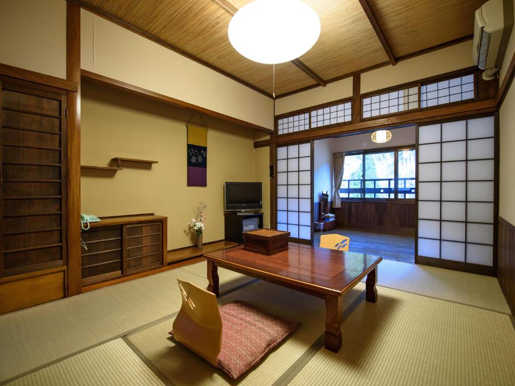 - un salon avec une table en bois et une porte dans l'établissement Yunohira Kamiyanagiya, à Yufu 37 autres photos