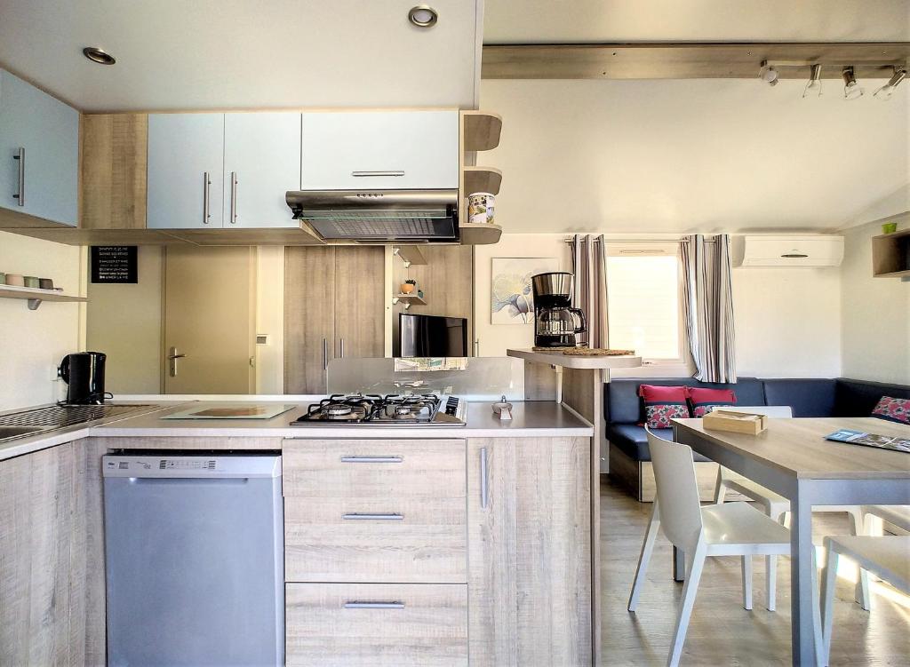 une cuisine avec des armoires blanches et une table et une salle à manger dans l'établissement Mobil Home 6/8 Places vue dégagée, au Muy