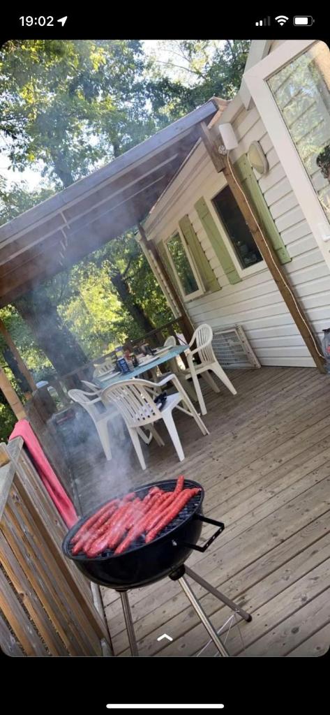 - un barbecue sur une terrasse avec une table de pique-nique et une table dans l'établissement Mobil-home Saint-Chéron 91530 Camping Parc des roches, à Mirgaudon