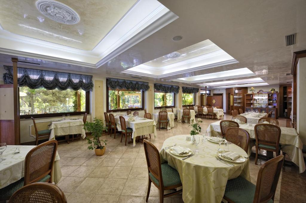 un restaurant avec des tables et des chaises blanches et des fenêtres dans l'établissement Park Hotel Villa Maria, à San Menaio