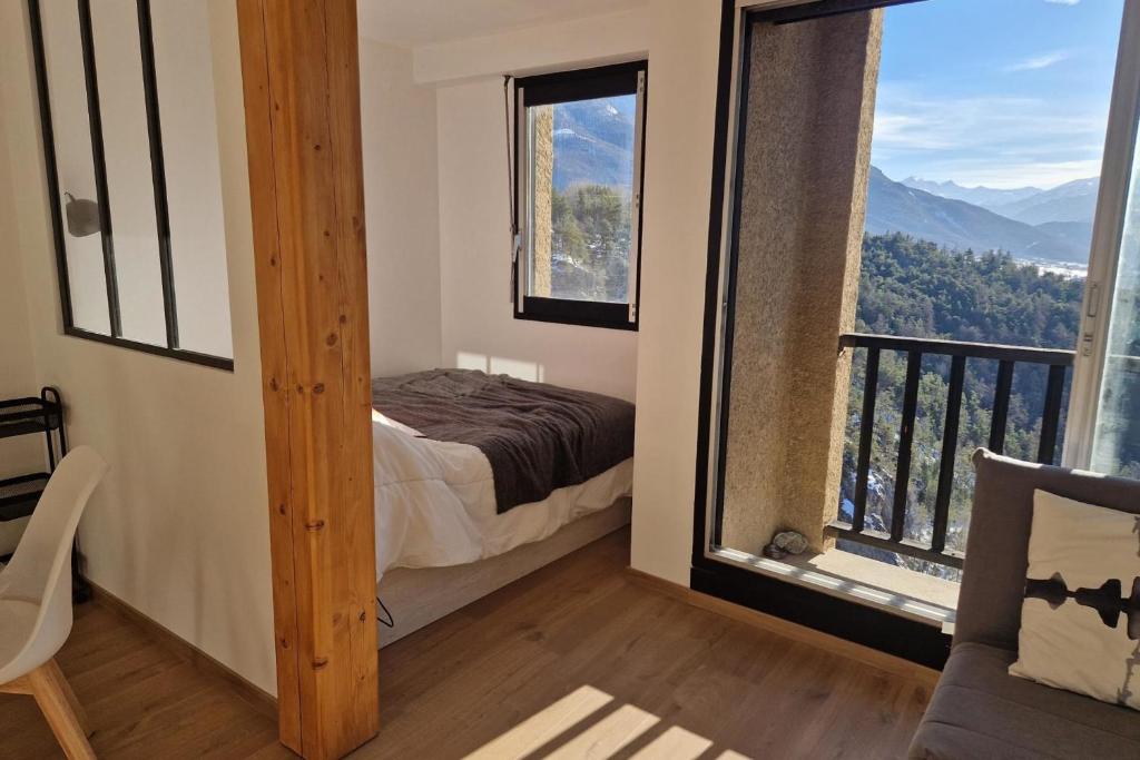 une chambre avec un lit et une grande fenêtre dans l'établissement Rare pearl with an incredible view of all Briançon, à Briançon