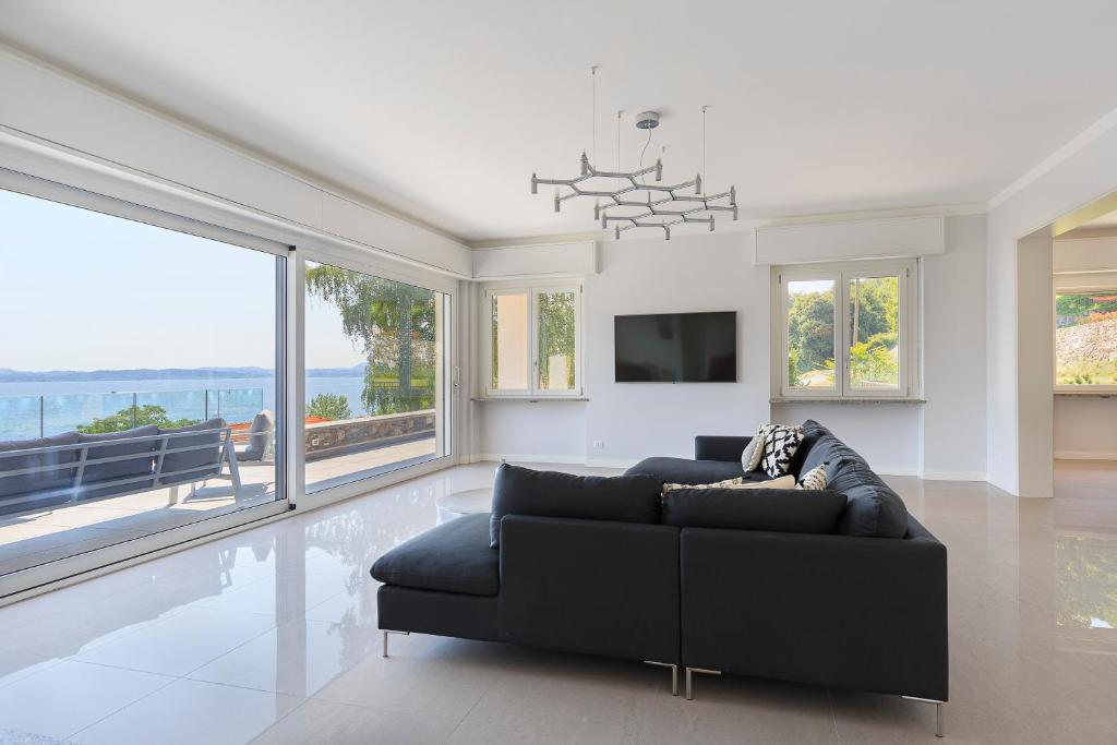 un salon avec un canapé noir et de grandes fenêtres dans l'établissement Villa Incanta by Casa da Suite, à Brisino