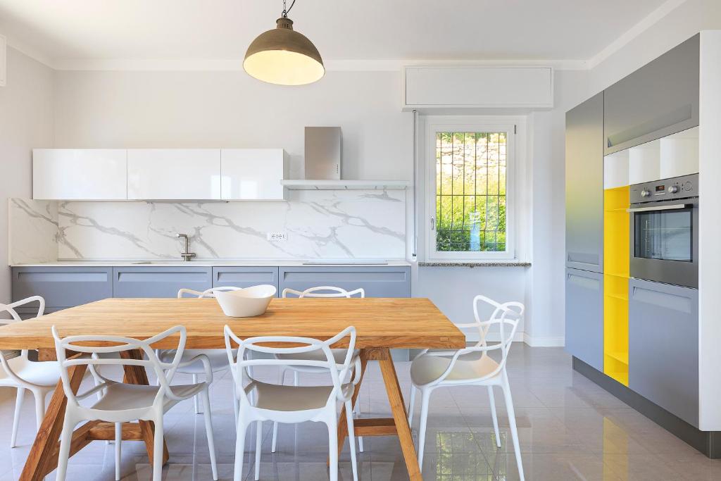 - une cuisine avec une table en bois et des chaises blanches dans l'établissement Villa Incanta by Casa da Suite, à Brisino