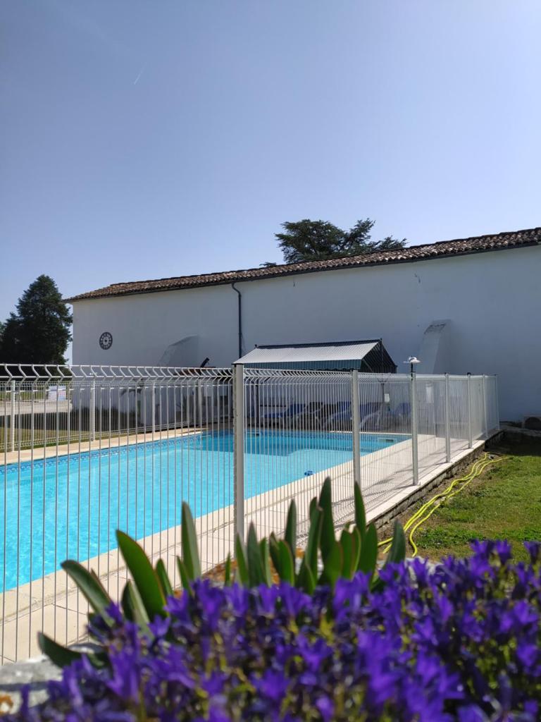 une clôture autour d'une piscine avec des fleurs violettes dans l'établissement Domaine Moulin d'Elemiah, à Gémozac