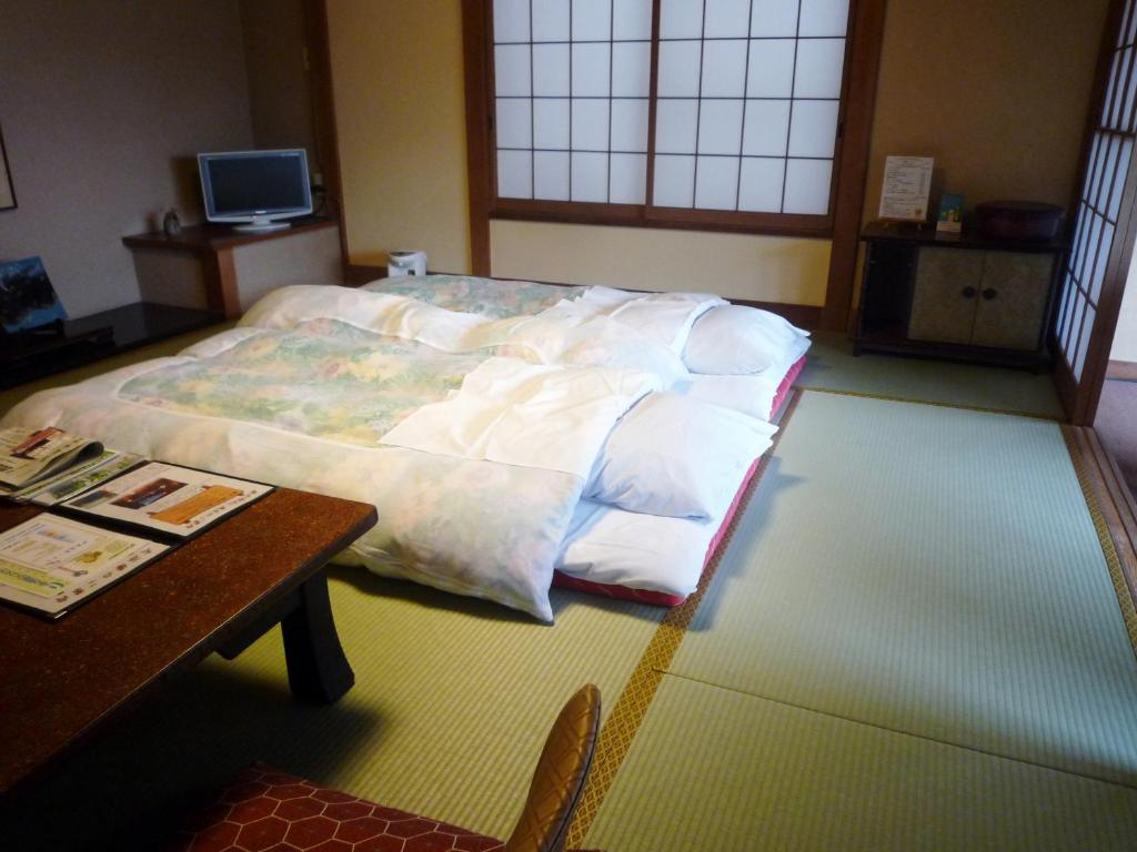 un grand lit dans une chambre avec une table dans l'établissement Yokikan, à Itō