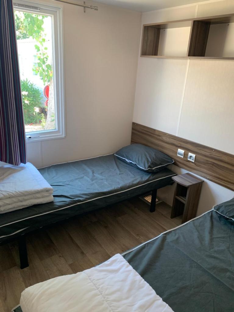 une chambre avec deux lits et une fenêtre dans l'établissement Mobilhome 5 VO32, à Vias