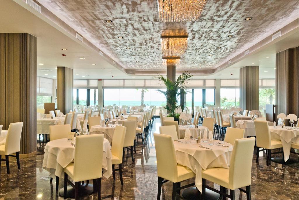 une salle de banquet avec des tables, des chaises et un lustre dans l'établissement Hotel Italy, à Bibione