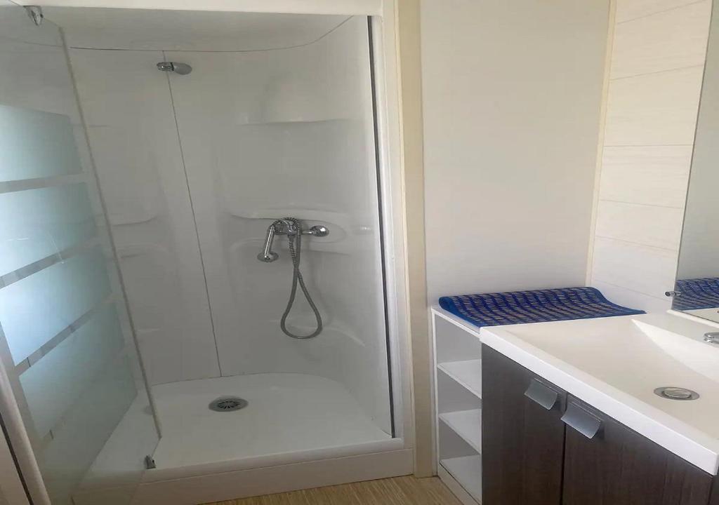 une douche avec une porte vitrée dans une salle de bain dans l'établissement La Roque d'Anthéron - Mobile-home - 6 pers - 3 ch - Piscine, à La Roque-dʼAnthéron