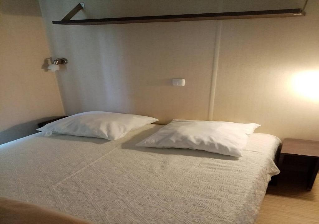 un lit avec deux oreillers dessus dans une chambre dans l'établissement La Roque d'Anthéron - Mobile-home - 6 pers - 3 ch - Piscine, à La Roque-dʼAnthéron
