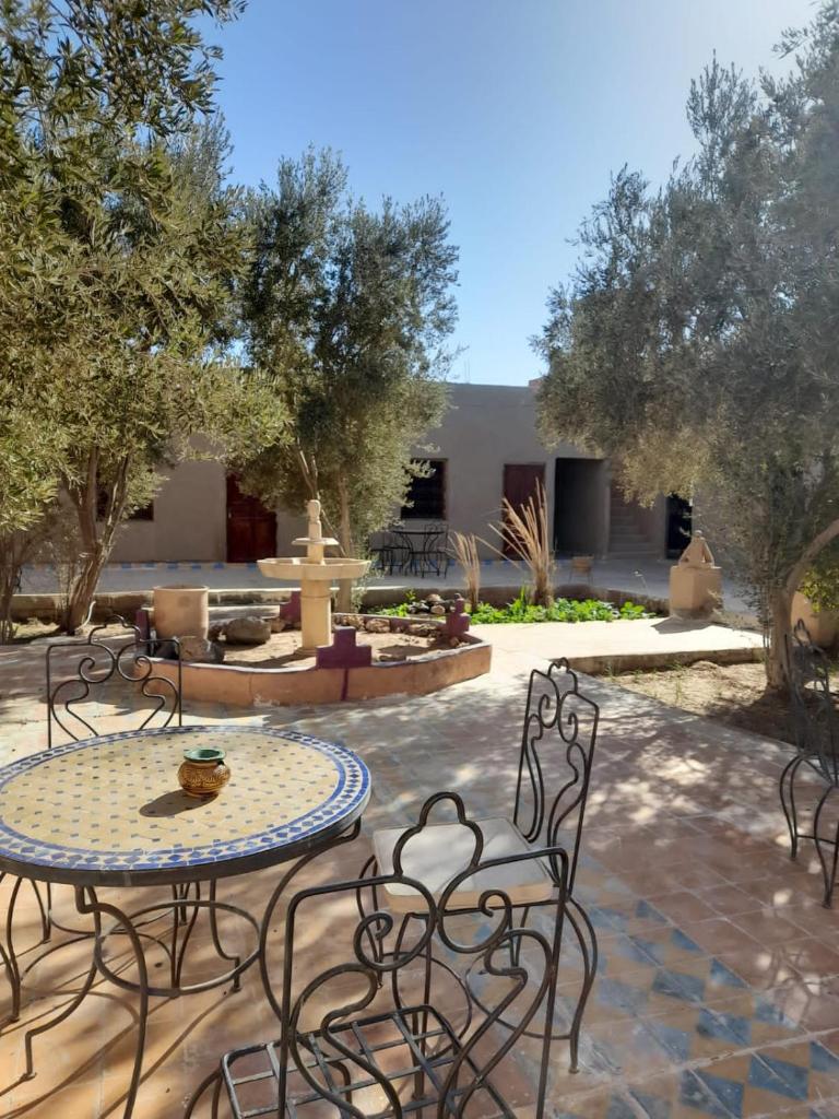 un patio avec une table, des chaises et une fontaine dans l'établissement Riad Akour, à Merzouga 32 autres photos