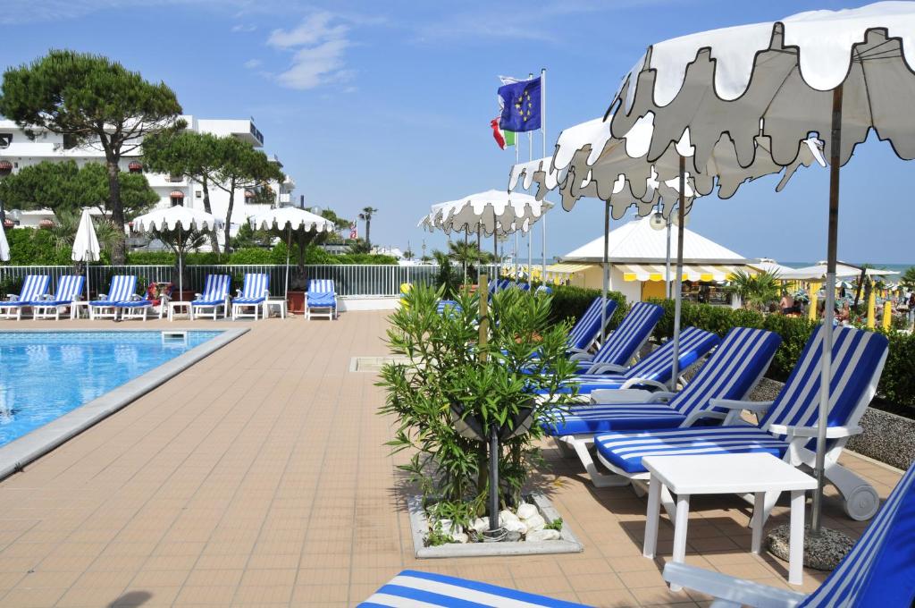 une rangée de chaises longues bleues à côté d'une piscine dans l'établissement Hotel Plaza Esplanade, à Lido di Jesolo