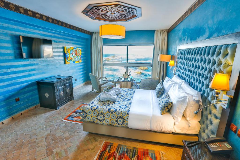 une chambre avec des murs bleus et un lit et une fenêtre dans l'établissement Riad Mimouna, à Essaouira