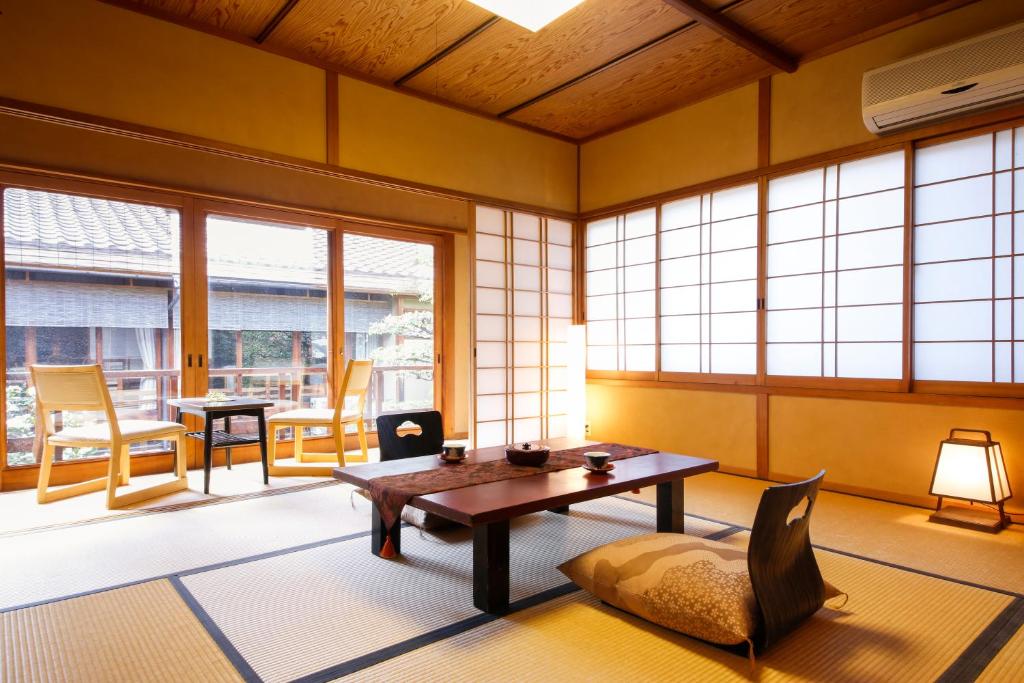 un salon avec une table, des chaises et des fenêtres dans l'établissement Ryokan Sanga, à Kyoto