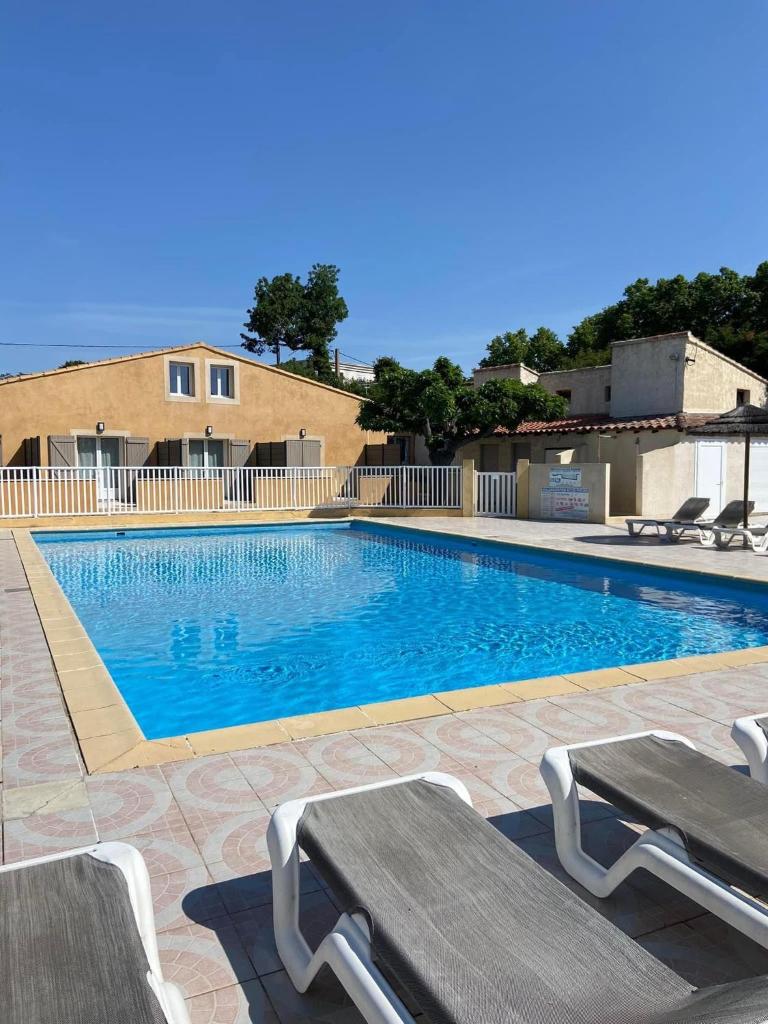 - une piscine avec 2 chaises longues à côté dans l'établissement Camping L' Arlesienne, à Arles