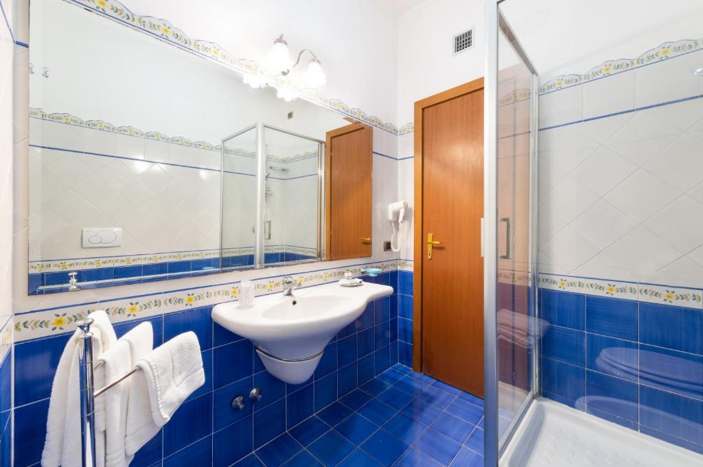 une salle de bain carrelée bleue avec un lavabo et une douche dans l'établissement Hotel Sporting, à Vico Equense