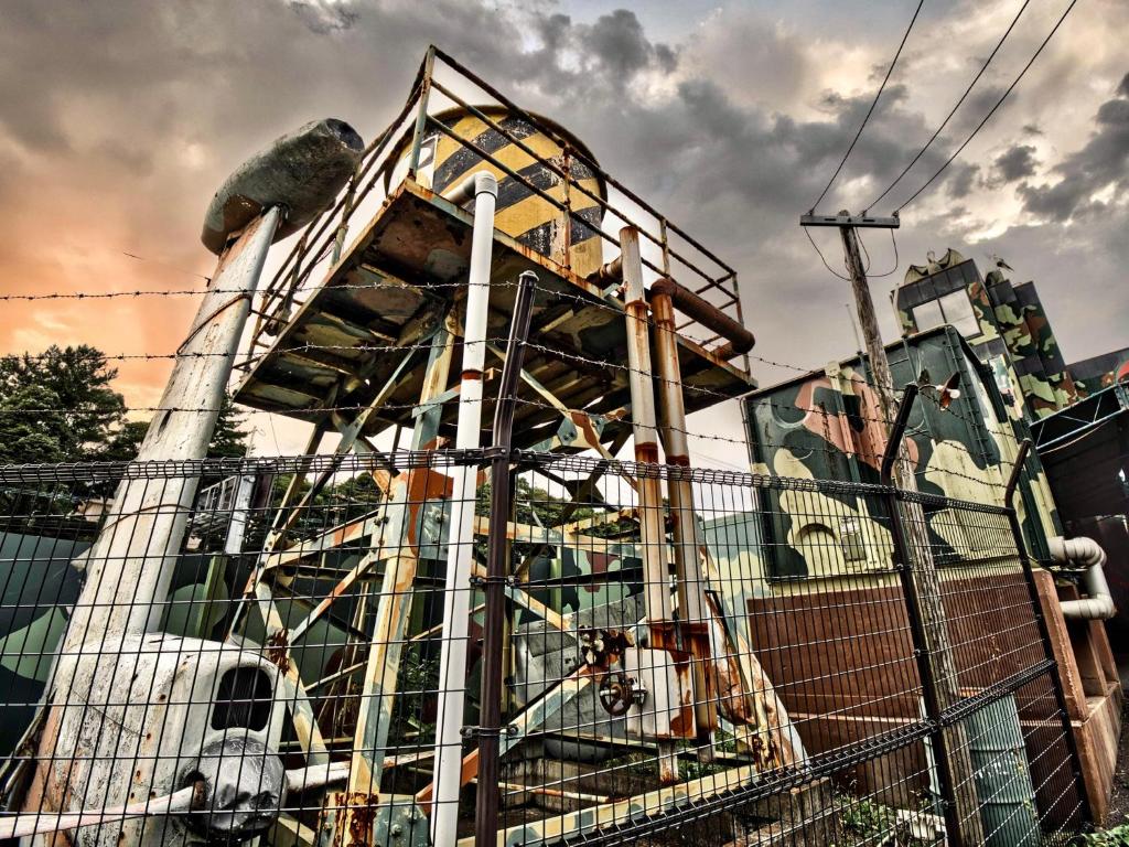 un bâtiment avec une clôture devant lui dans l'établissement SKY JZauruss バズるホテル ,Dinosaur Love Hotel, à Beppu 24 autres photos