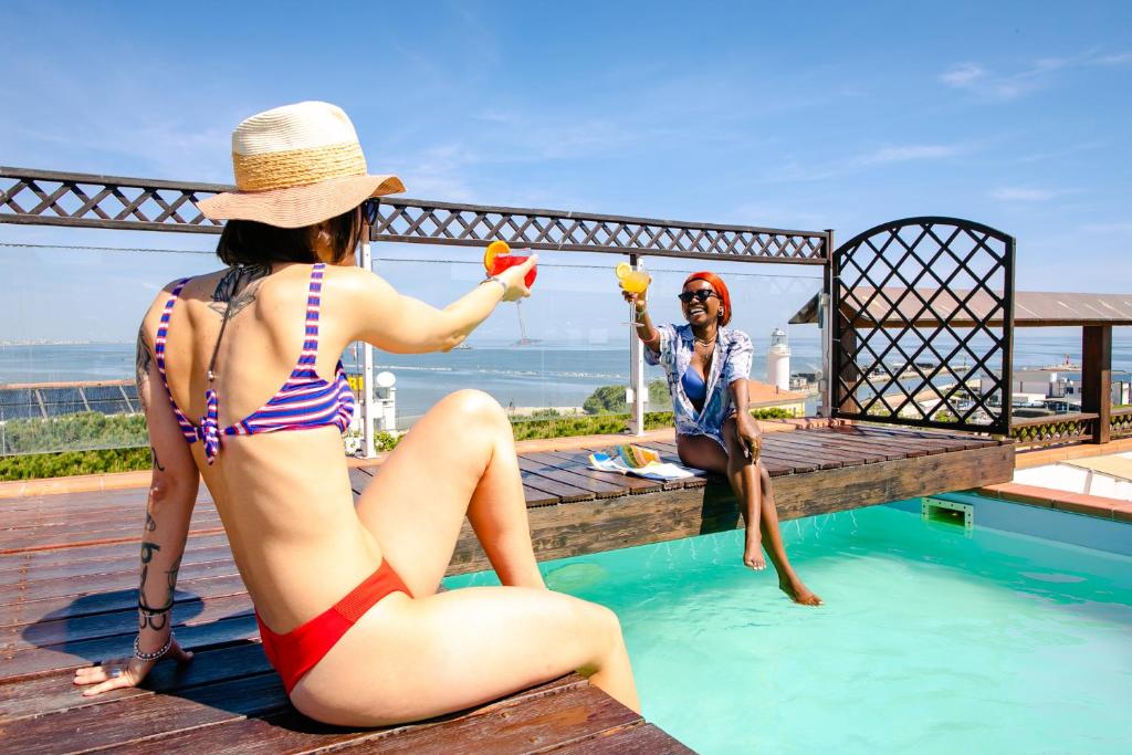 - deux femmes en maillot de bain assises à côté d'une piscine dans l'établissement B&B Domus Mea, à Cesenatico