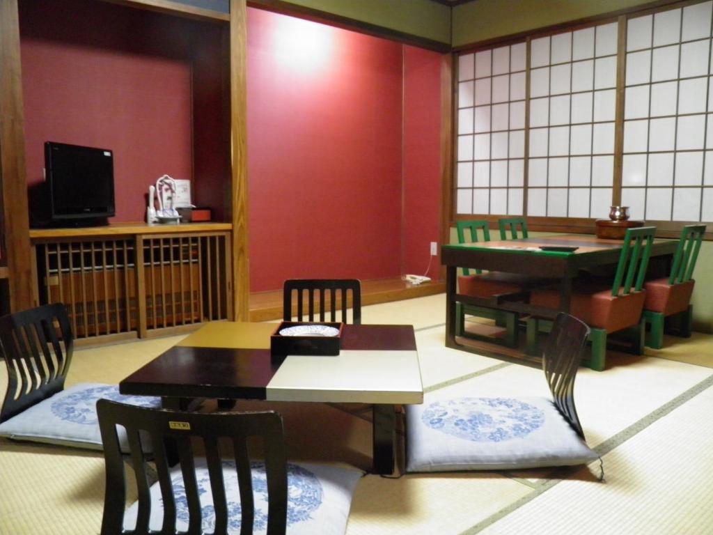 une pièce avec une table, des chaises et une télévision dans l'établissement Wakanoyu, à Chikuma