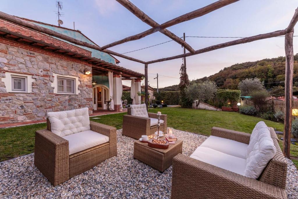 un patio avec des meubles en osier et une maison en pierre dans l'établissement Rondini, Farmhouse with pool, à Chiatri
