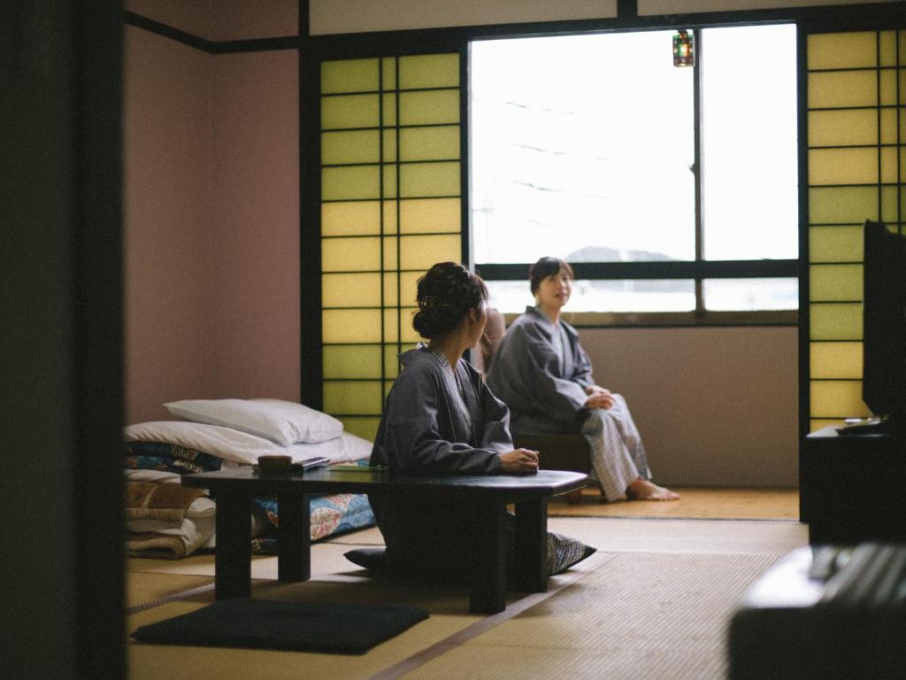 2 personnes assises à une table dans une pièce avec fenêtre dans l'établissement Wakatake, à Katsuura