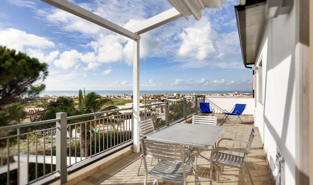 un balcon avec une table et des chaises et la plage dans l'établissement Sikelika Residence Sul Mare, à Scoglitti