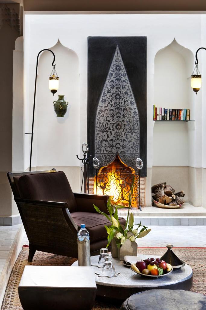 un salon avec une table et une cheminée dans l'établissement Le Farnatchi, à Marrakech