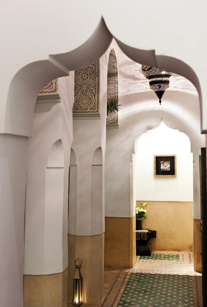un couloir d'une mosquée avec des murs et des plafonds blancs dans l'établissement Le Farnatchi, à Marrakech