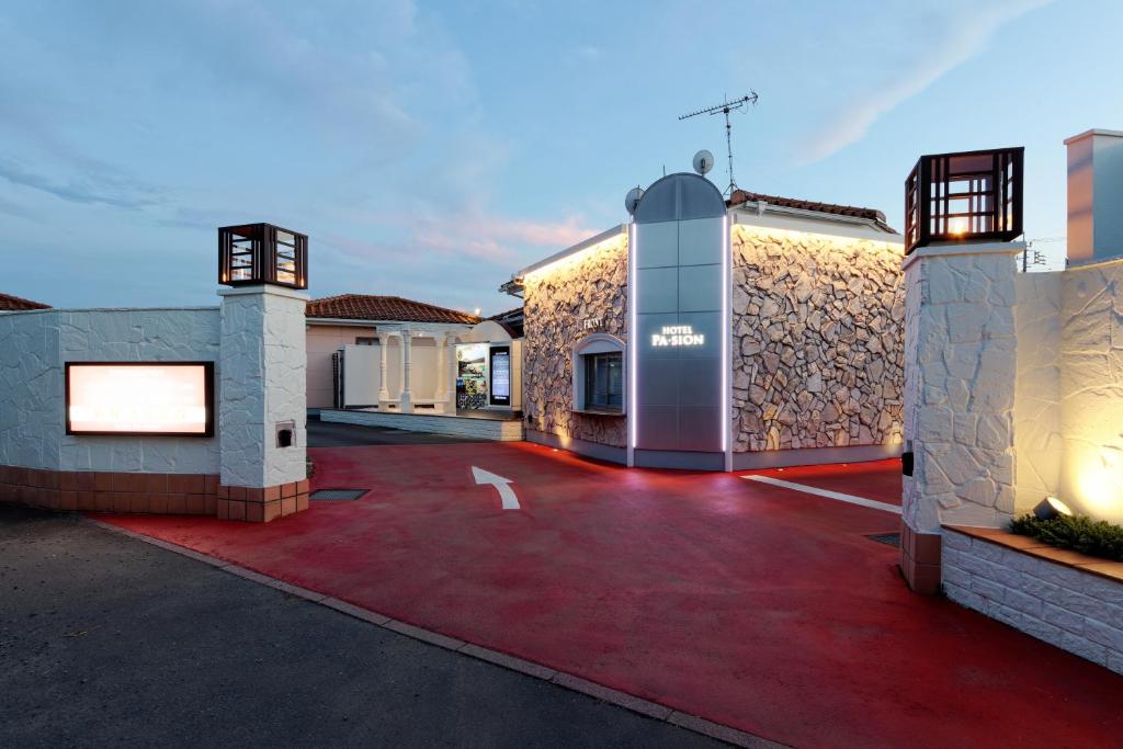 - un bâtiment avec une allée rouge en face dans l'établissement ホテルパシオンリゾート, à Matsuyama