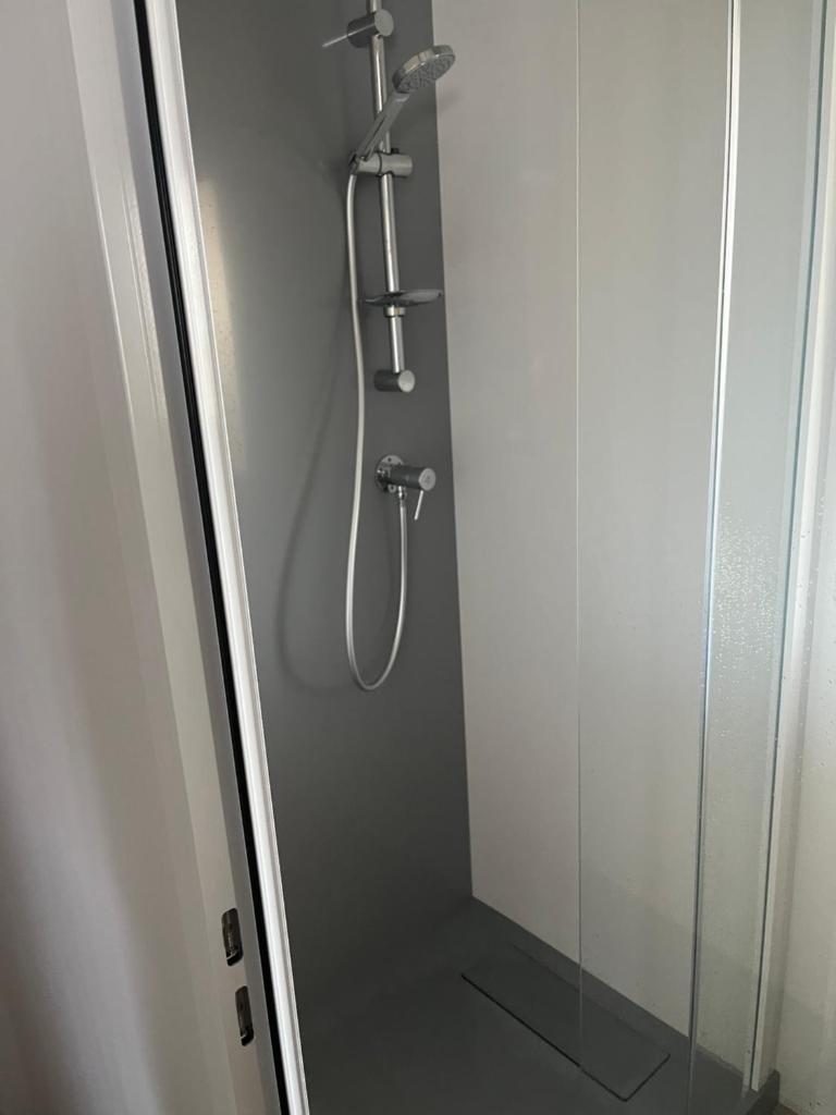 une douche dans une salle de bain avec une porte vitrée dans l'établissement MH 3 chambres, camping Les Dunes de Contis, Landes, à Saint-Julien-en-Born