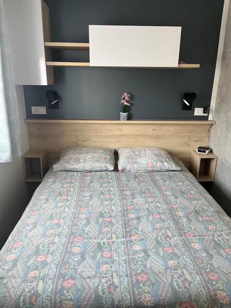 une chambre avec un lit avec une couette dessus dans l'établissement MH 3 chambres, camping Les Dunes de Contis, Landes, à Saint-Julien-en-Born