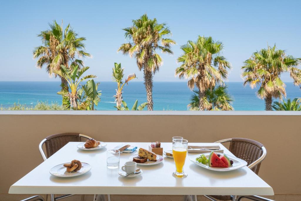 - une table avec deux assiettes de nourriture et une vue sur l'océan dans l'établissement Hotel Villaggio Cala Di Volpe, à Capo Vaticano